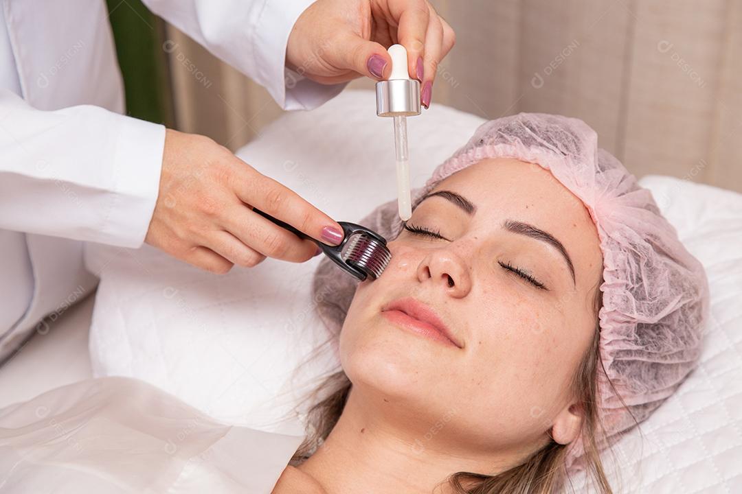 Rosto feminino de close up com dermaroller para procedimentos de mesoterapia
