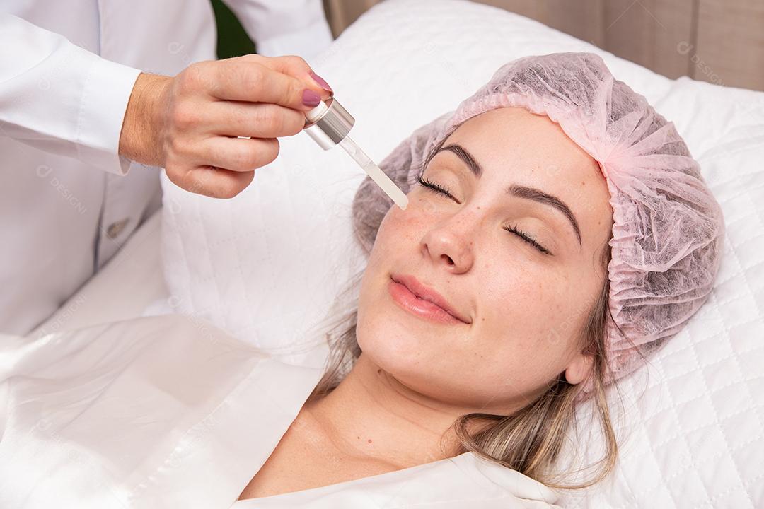 Mulher jovem e bonita com óleo cosmético no spa