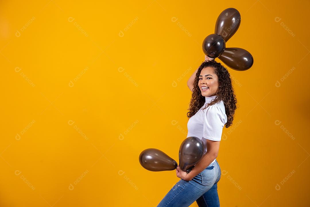 Mulher afro com balões pretos comemorando ofertas de aniversário