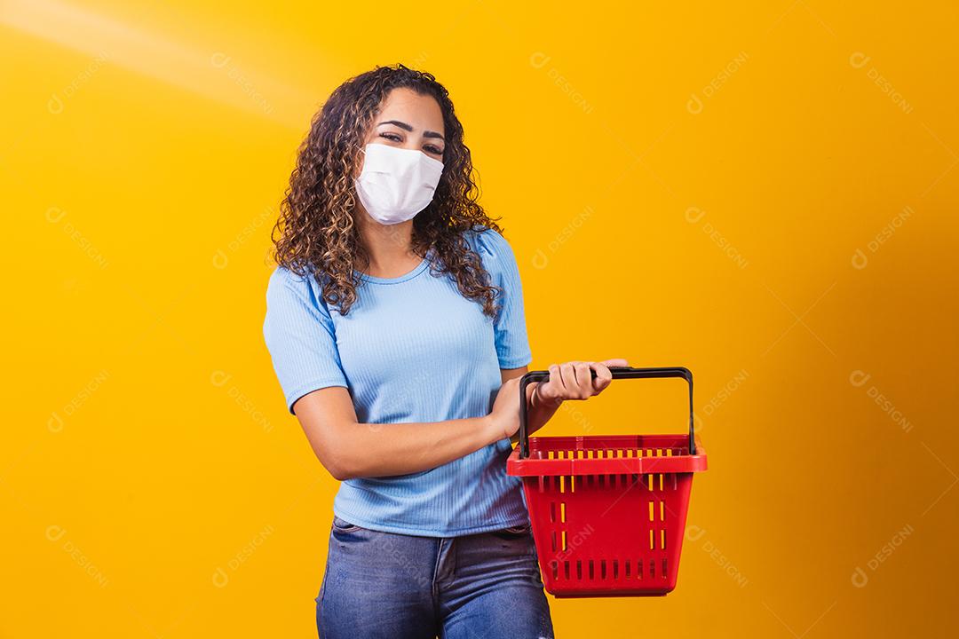 Jovem Mulher Afro Americana de Máscara com tranças usando cesta de compras