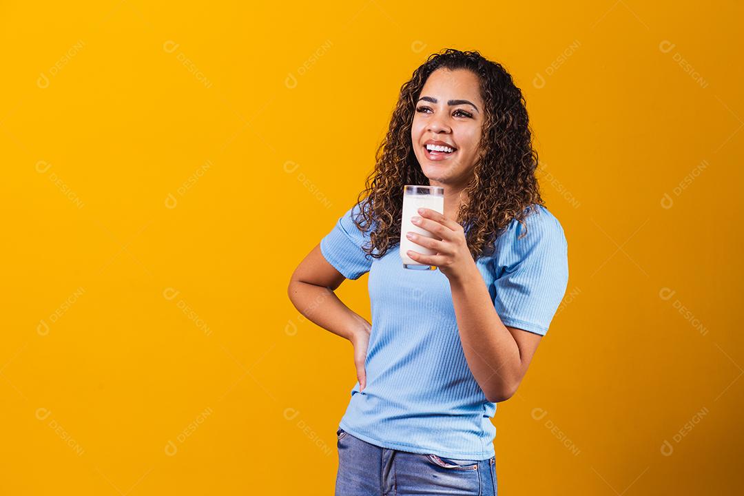 Jovem bebendo um copo de leite e segurando a garrafa cheia.