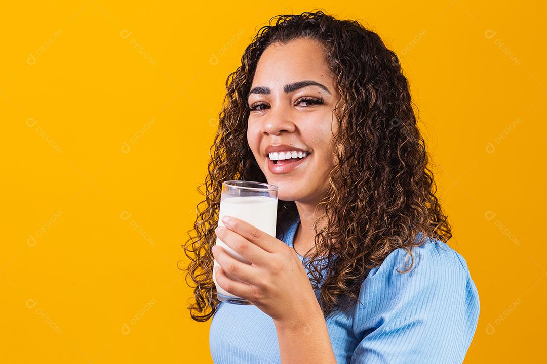 Jovem bebendo um copo de leite e segurando a garrafa cheia.