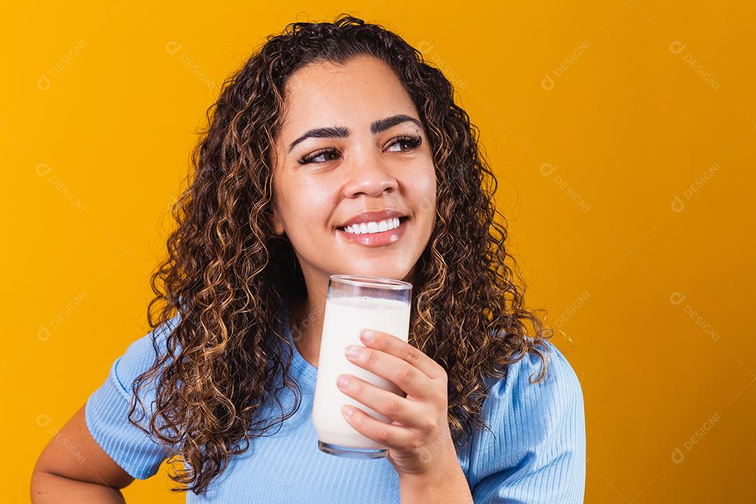 Jovem bebendo um copo de leite e segurando a garrafa cheia.