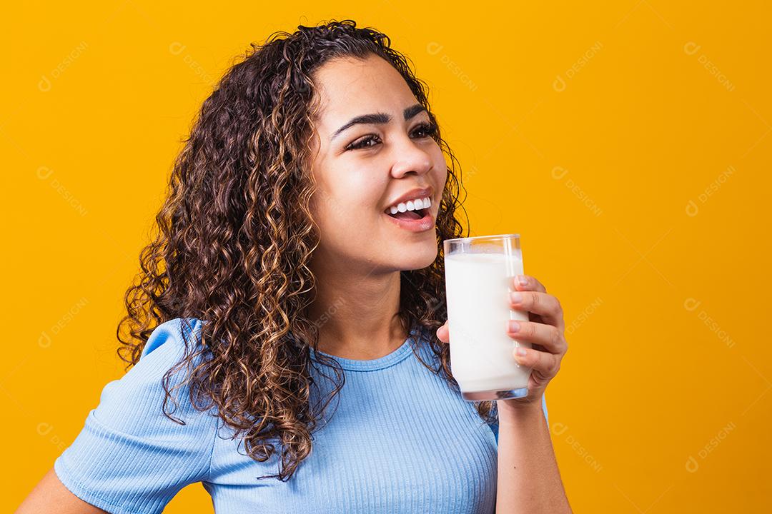 Jovem bebendo um copo de leite e segurando a garrafa cheia.