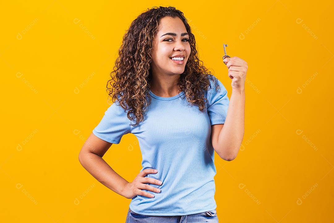 Jovem afro segurando uma chave de casa.