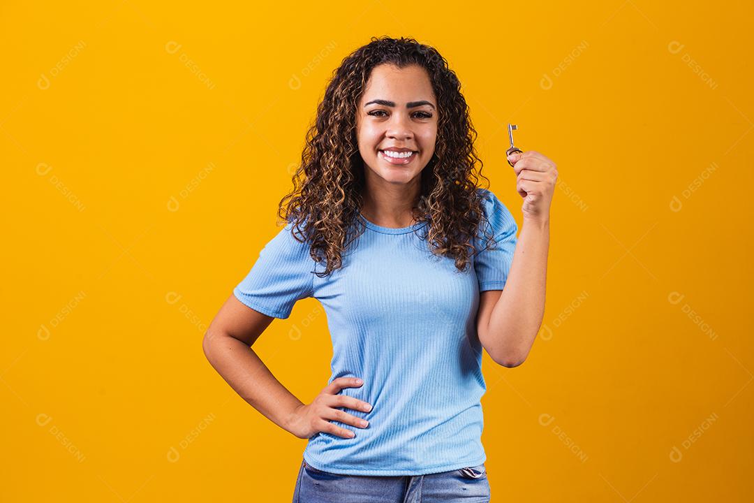 Jovem afro segurando uma chave de casa.