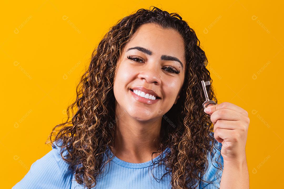 Jovem afro segurando uma chave de casa.