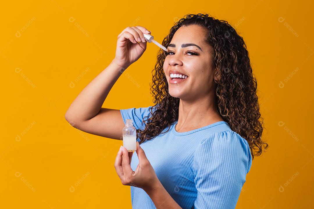 Mulher jovem e bonita com óleo cosmético na cor de fundo