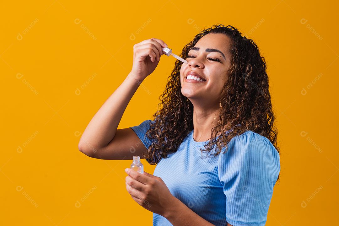 Mulher jovem e bonita com óleo cosmético na cor de fundo