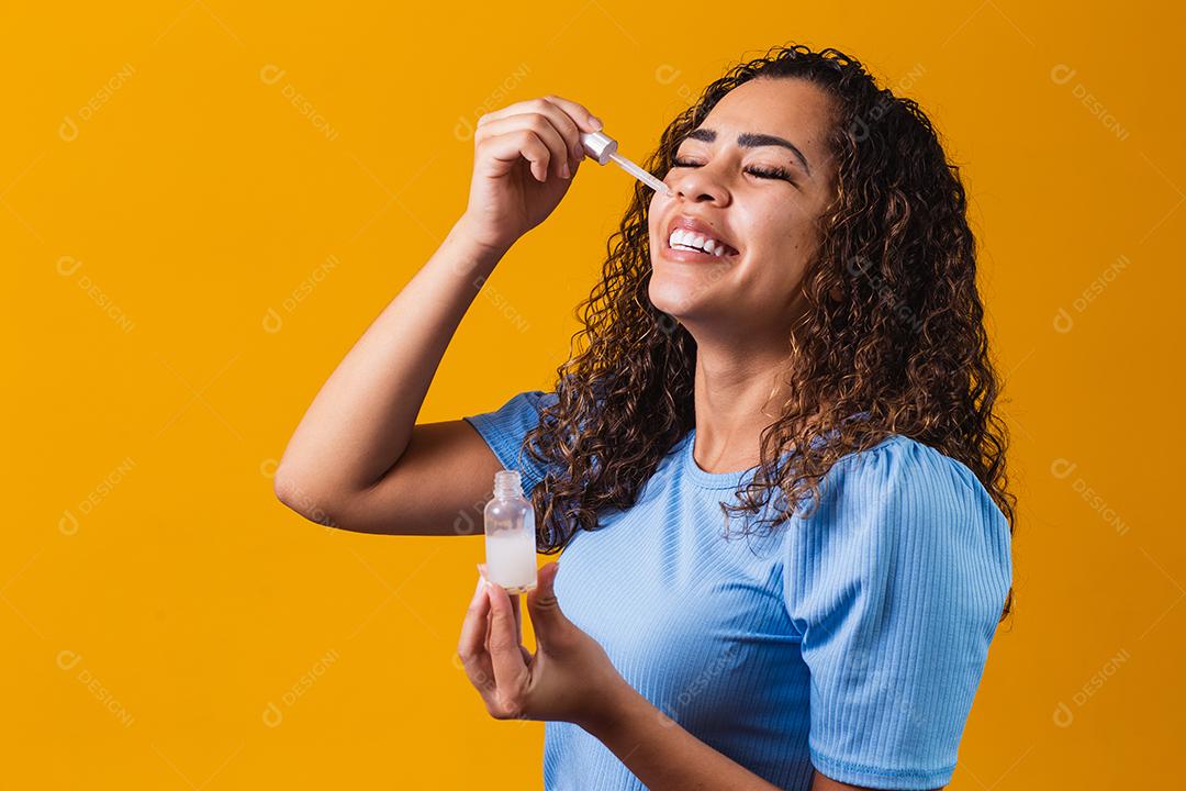 Mulher jovem e bonita com óleo cosmético na cor de fundo