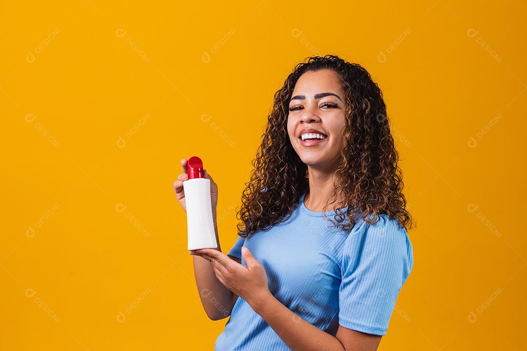 mulher segurando um creme em fundo amarelo
