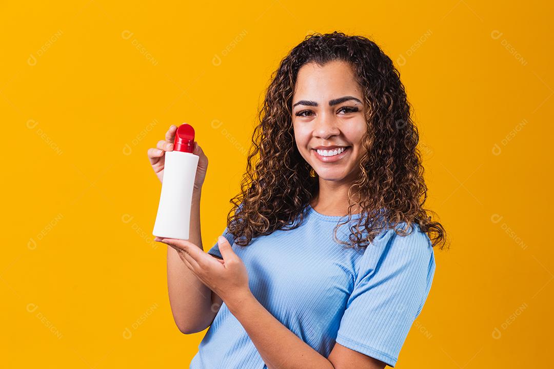 mulher segurando um creme em fundo amarelo