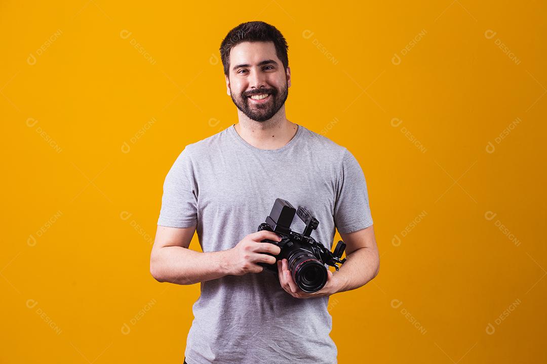 Rapaz com uma câmera fotográfica na mão. Belo fotógrafo em um fundo amarelo