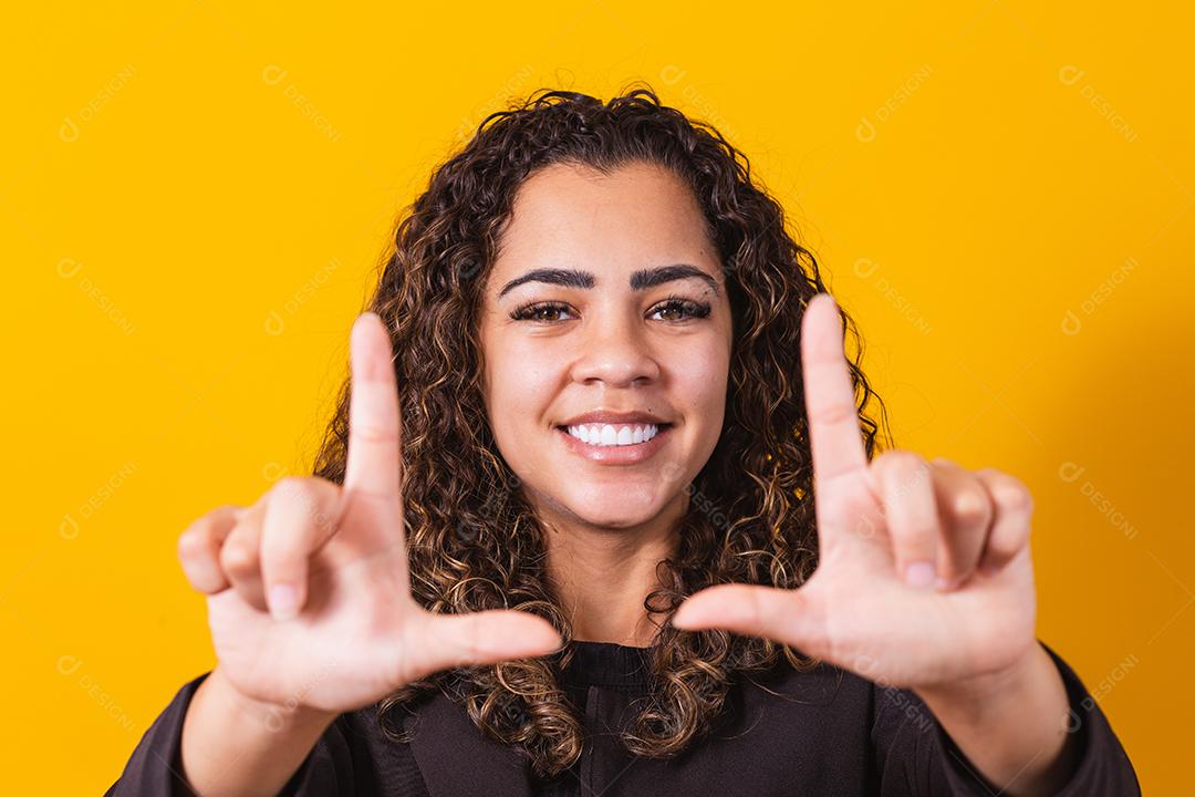 Jovem afro-americana vestindo roupas executivas sorrindo fazendo molduras para fotos com as mãos e os dedos