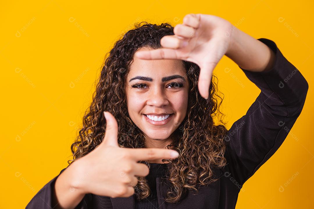 Jovem afro-americana vestindo roupas executivas sorrindo fazendo molduras para fotos com as mãos e os dedos