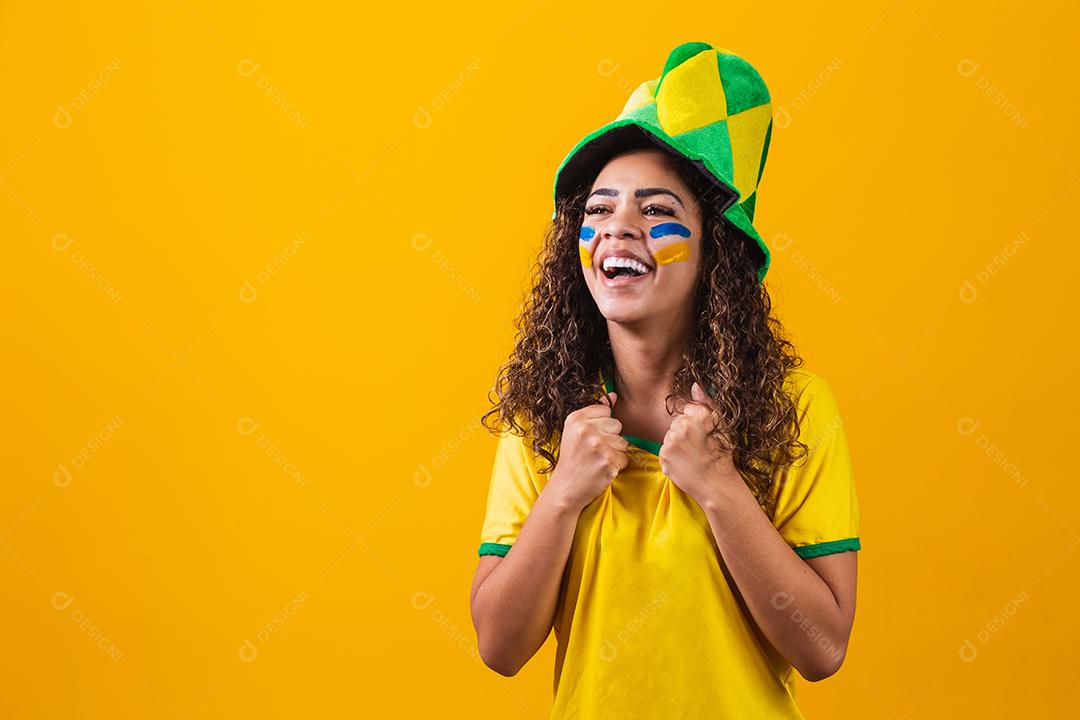 Fã brasileiro. Fã brasileiro comemorando jogo de futebol ou futebol em fundo amarelo. Cores do Brasil.