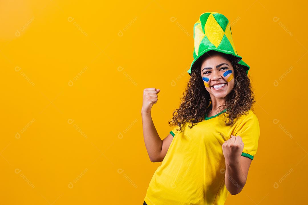 torcedor brasileiro. Fã de mulher brasileira comemorando no futebol ou partida de futebol em fundo amarelo. Cores do Brasil. Sim!