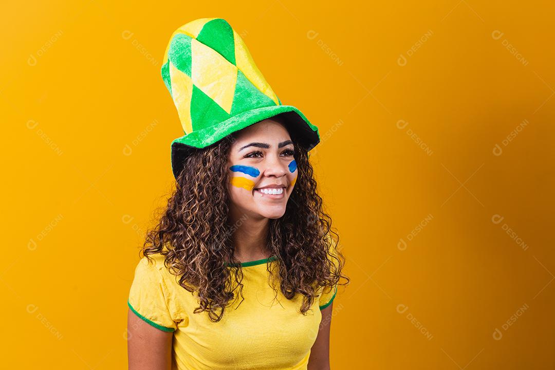 torcedor brasileiro. Fã de mulher brasileira comemorando no futebol ou partida de futebol em fundo amarelo. Cores do Brasil. Sim!