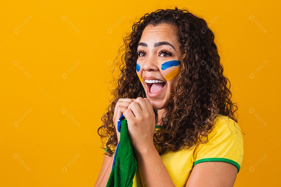fã brasileiro com bandeira rezando sobre fundo amarelo. orando pelo brasil