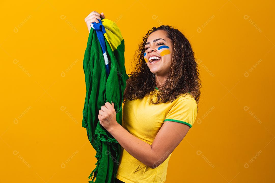 fã brasileiro com bandeira rezando sobre fundo amarelo. orando pelo brasil