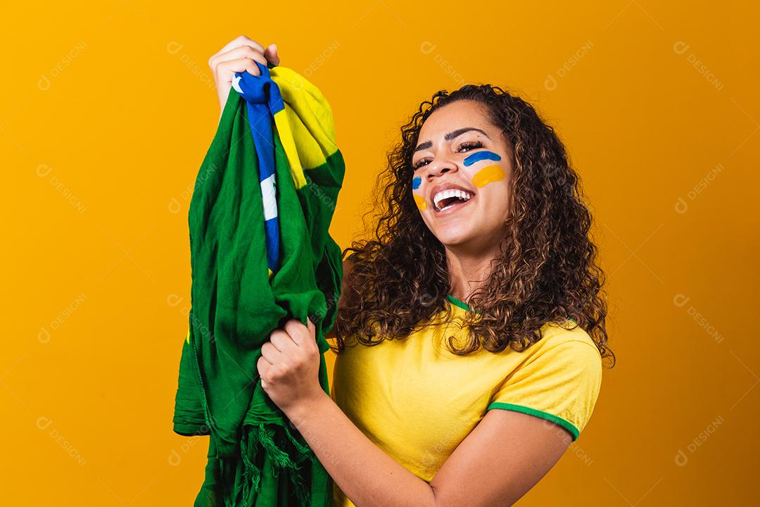 fã brasileiro com bandeira rezando sobre fundo amarelo. orando pelo brasil