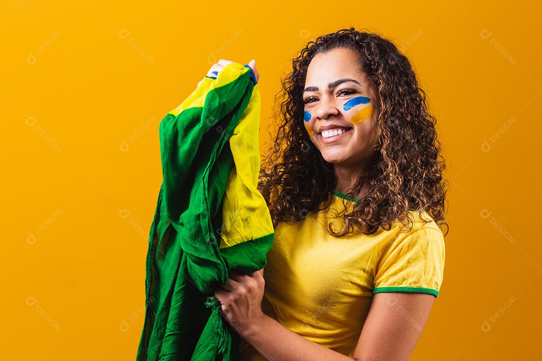 fã brasileiro com bandeira rezando sobre fundo amarelo. orando pelo brasil