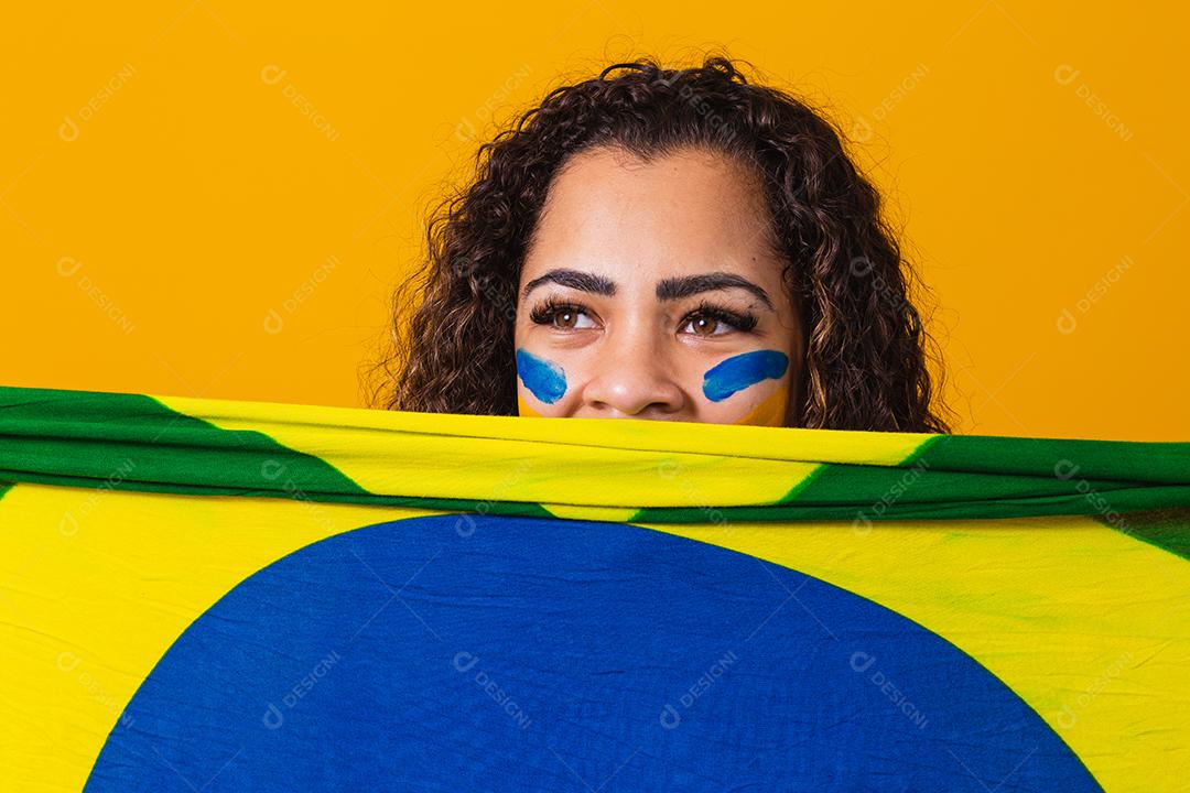 Fã misteriosa mulher negra segurando uma bandeira brasileira na sua cara