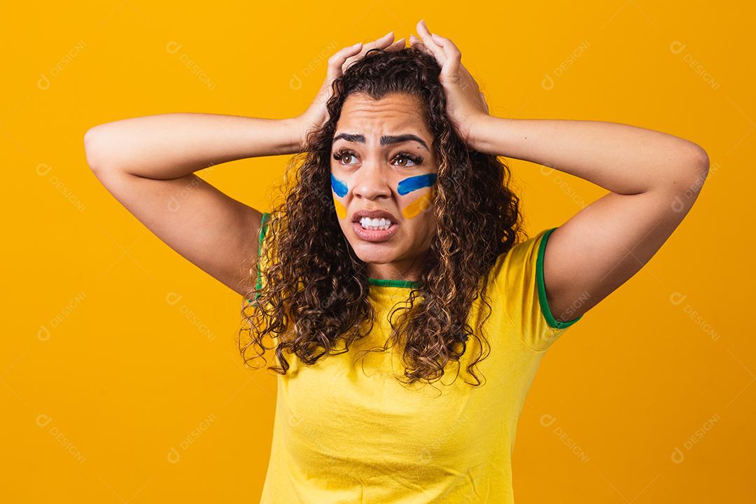 Torcedor brasileiro animado e nervoso com o jogo em um fundo amarelo