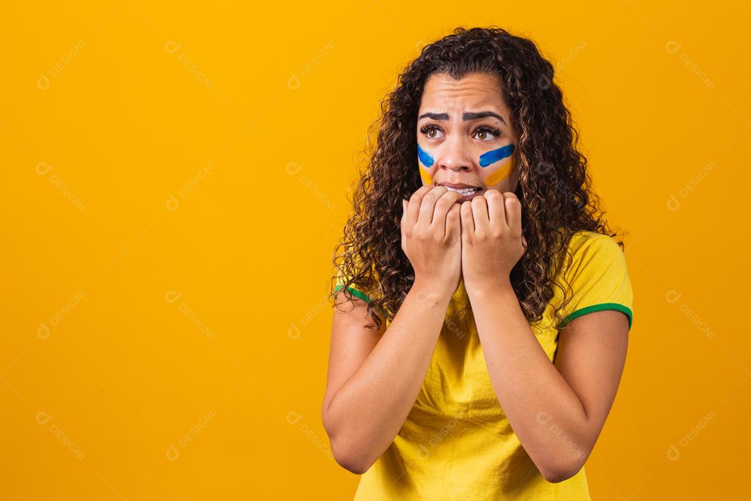 Torcedor brasileiro animado e nervoso com o jogo em um fundo amarelo