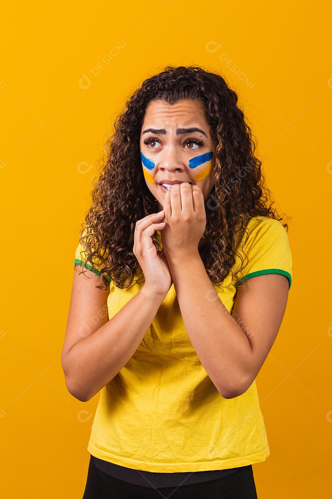 Torcedor brasileiro animado e nervoso com o jogo em um fundo amarelo