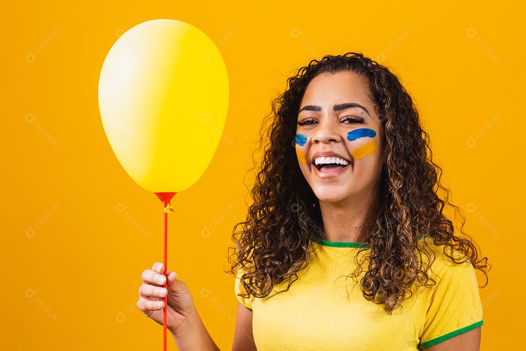 fã brasileiro segurando um balão amarelo com espaço livre para texto. promoção de jogos do brasil