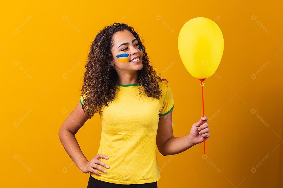 fã brasileiro segurando um balão amarelo promoção de jogos do brasil