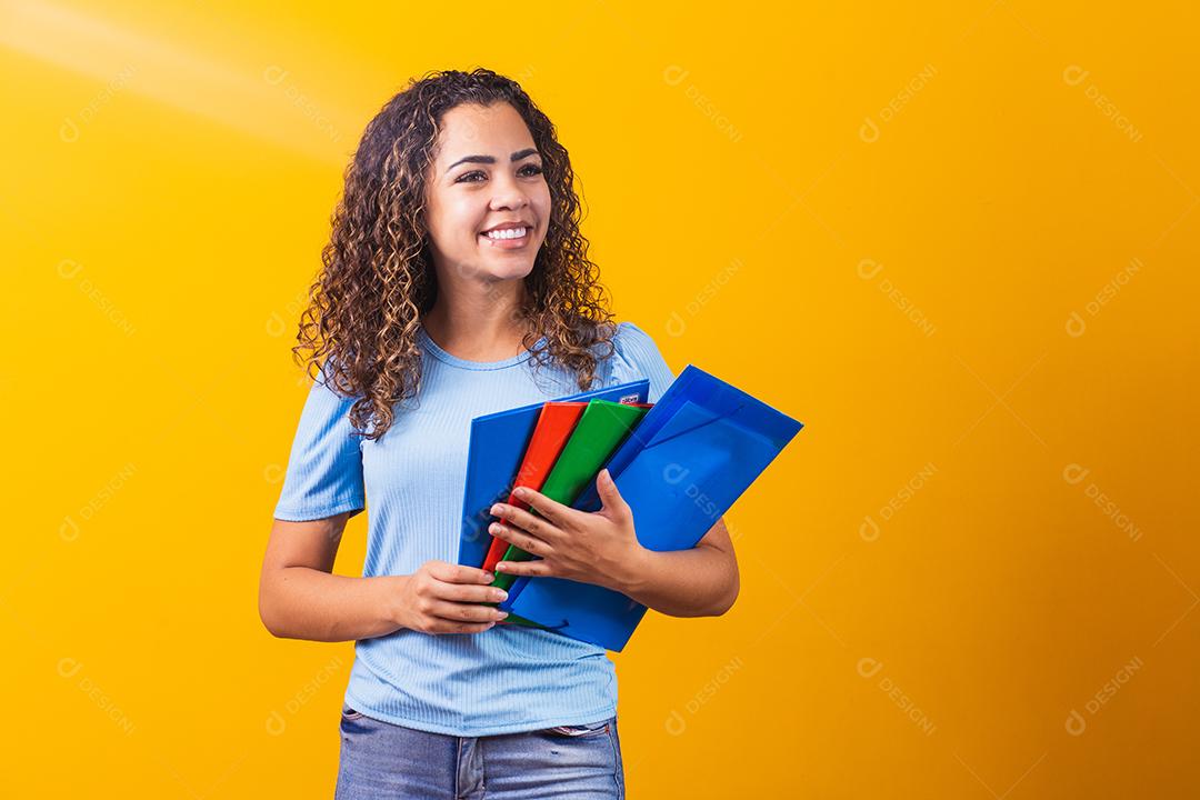 Jovem estudante adolescente afro-americano em roupas casuais, segurando livros isolados no retrato de estúdio