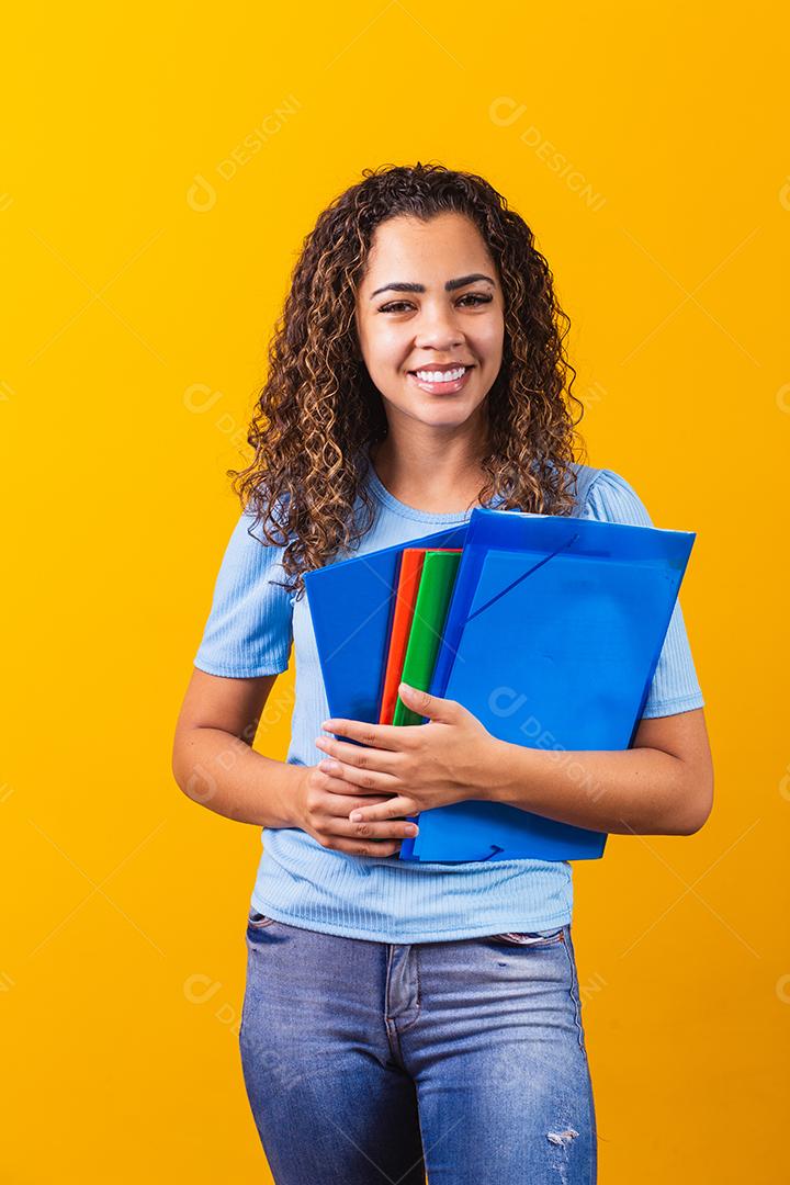Jovem estudante adolescente afro-americano em roupas casuais, segurando livros isolados no retrato de estúdio