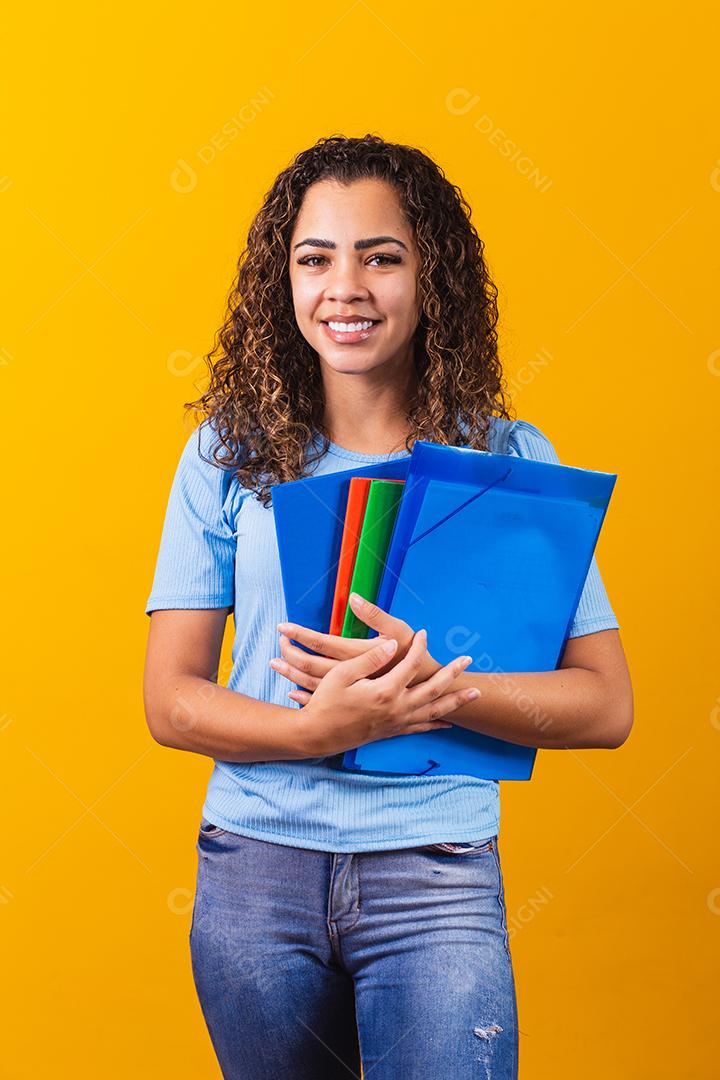 Jovem estudante adolescente afro-americano em roupas casuais, segurando livros isolados no retrato de estúdio