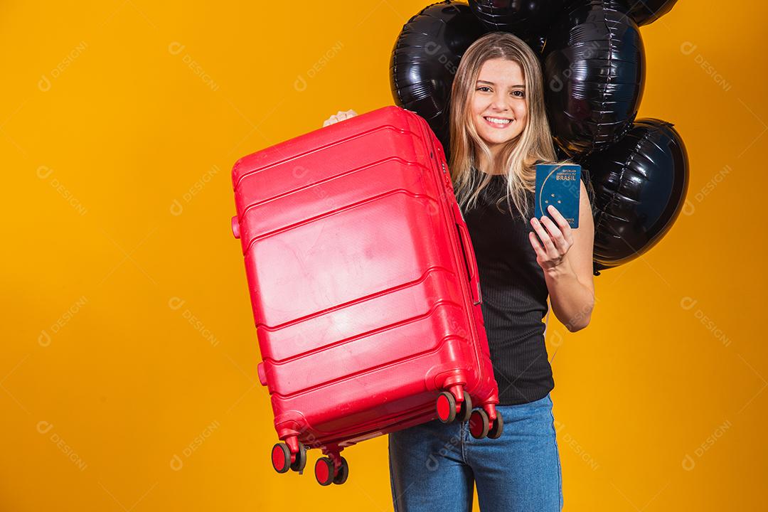 Linda loira de cabelos lisos em viagens. Próxima viagem. Garota segurando passaporte brasileiro. Em fundo amarelo. viagem de sexta-feira negra