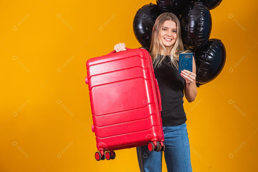 Linda loira de cabelos lisos em viagens. Próxima viagem. Garota segurando passaporte brasileiro. Em fundo amarelo. viagem de sexta-feira negra