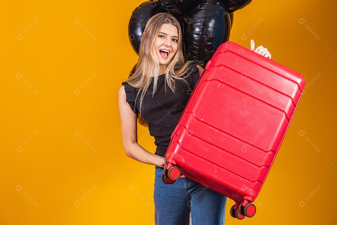 Mulher engraçada segurando uma mala de viagem pesada. Aniversário de promoção de viagens. Black Friday em bilhetes de viagem.