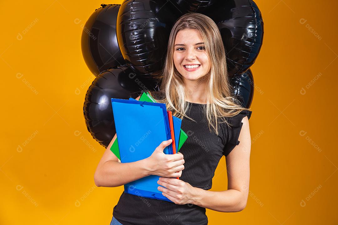 jovem mulher caucasiana sorrindo com notebooks nas mãos indo para a universidade na sexta-feira negra. conceito de equilíbrio na educação