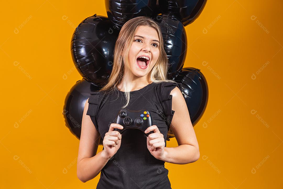 Promoção de black friday em eletrônicos. Jovem segurando um controlador de videogame em fundo amarelo