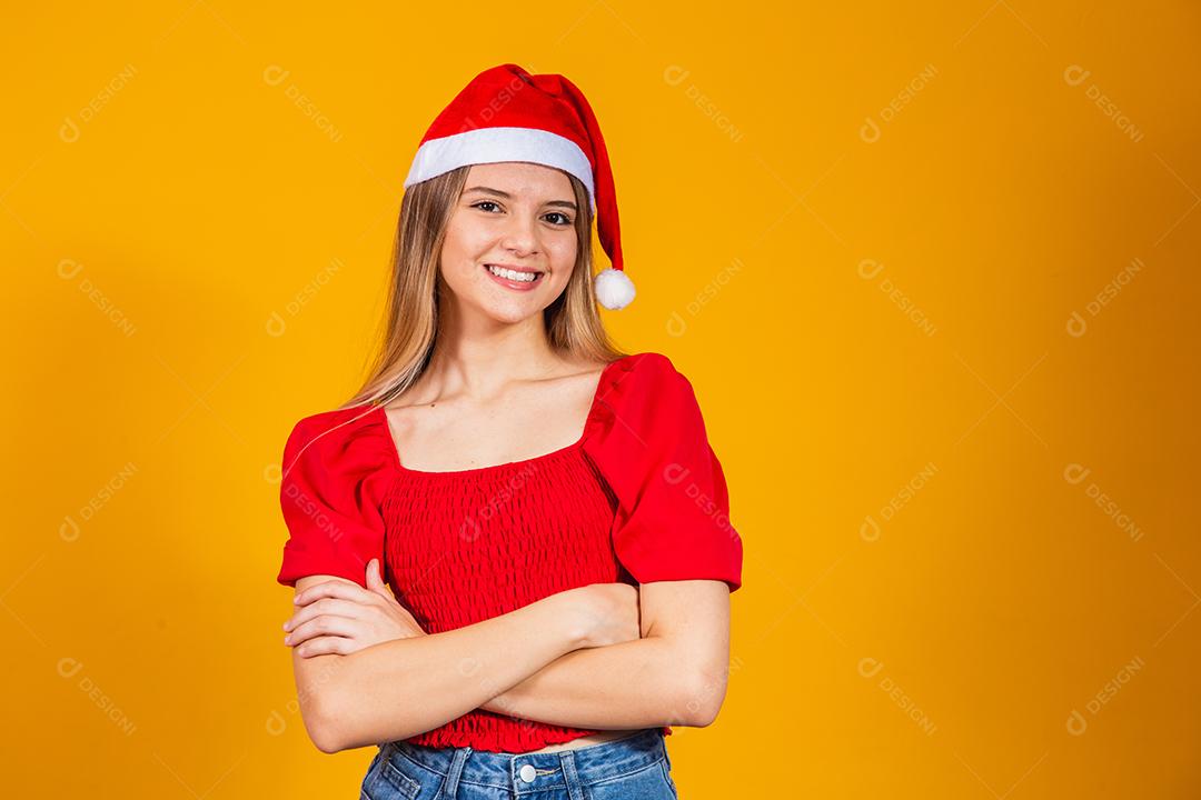 Jovem mulher bonita sobre fundo isolado com cara feliz de chapéu de Natal sorrindo com os braços cruzados, olhando para a câmera. Pessoa positiva.