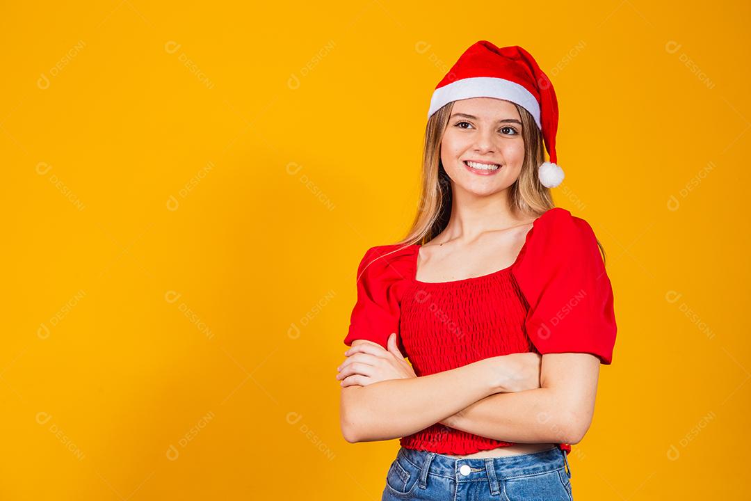Jovem mulher bonita sobre fundo isolado com cara feliz de chapéu de Natal sorrindo com os braços cruzados