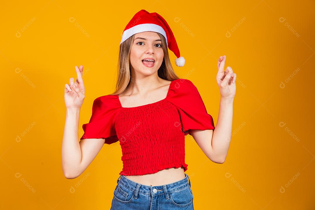 A imagem de uma jovem feliz e positiva isolada sobre o fundo da parede amarela faz um gesto esperançoso por favor