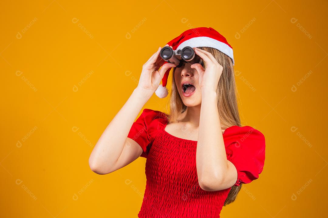 retrato de uma jovem vestindo uma roupa de natal olhando através de um binóculo