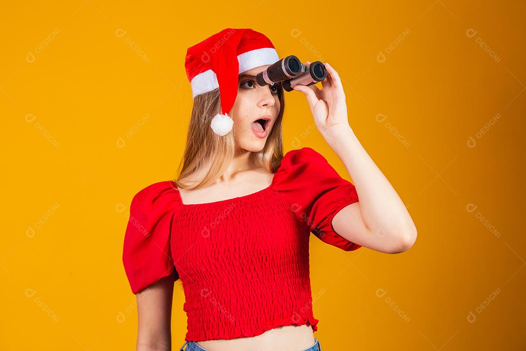 retrato de uma jovem vestindo uma roupa de natal olhando através de um binóculo