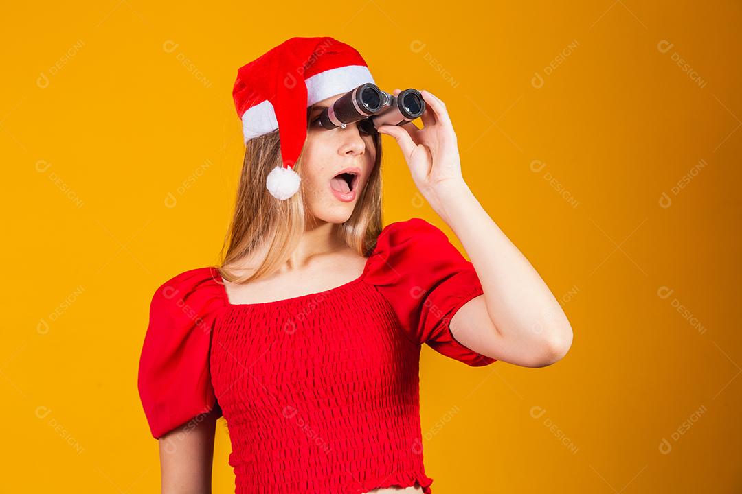 retrato de uma jovem vestindo uma roupa de natal olhando através de um binóculo
