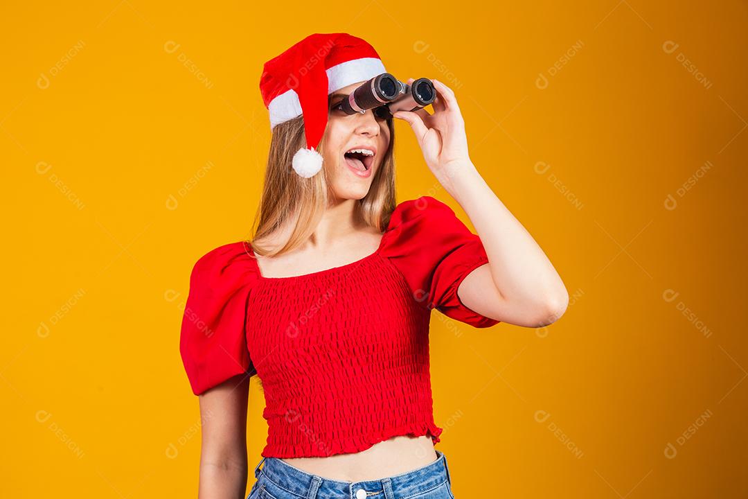 retrato de uma jovem vestindo uma roupa de natal olhando através de um binóculo