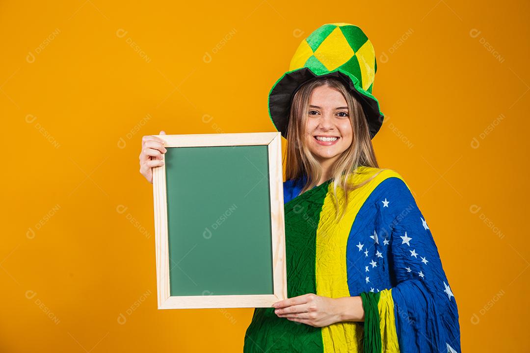 Mulher segurando Quadro Torcedora do brasil com chapéu e bandeira e expressão de felicidade
