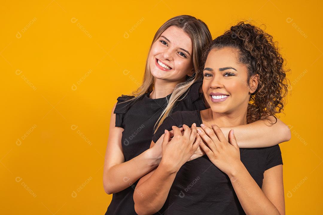 namoradas loiras e afro em fundo amarelo. Uma mulher loira branca e uma morena afro, conceito de diversidade