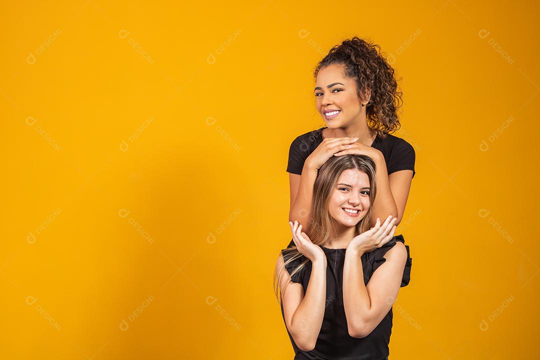 amigas de diferentes etnias abraçados em fundo amarelo
